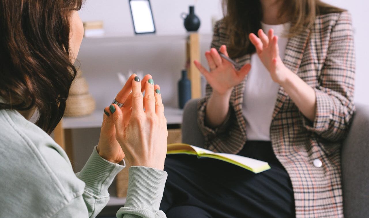 Crop unrecognizable female psychologist and patient discussing mental problems during session